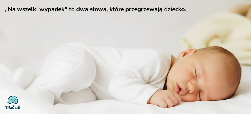 Śpiące niemowlę w białym pajacyku z długim rękawem, leżące na boku na białej pościeli. Obok kadru zwinięty jasnożółty kocyk. Slogan na grafice: Na wszelki wypadek to dwa słowa, które przegrzewają dziecko.